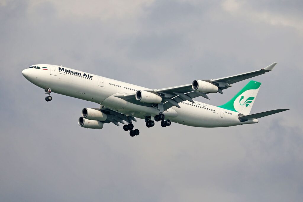 Mahan Air Airbus A340 captured mid-flight against a cloudy sky, showcasing aviation dynamics.