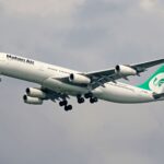 Mahan Air Airbus A340 captured mid-flight against a cloudy sky, showcasing aviation dynamics.