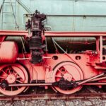 Detailed close-up of a vintage steam locomotive's wheels and mechanical parts. Industrial and historical charm.
