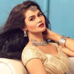 Portrait of a beautiful Indian woman in traditional jewelry posing elegantly indoors.