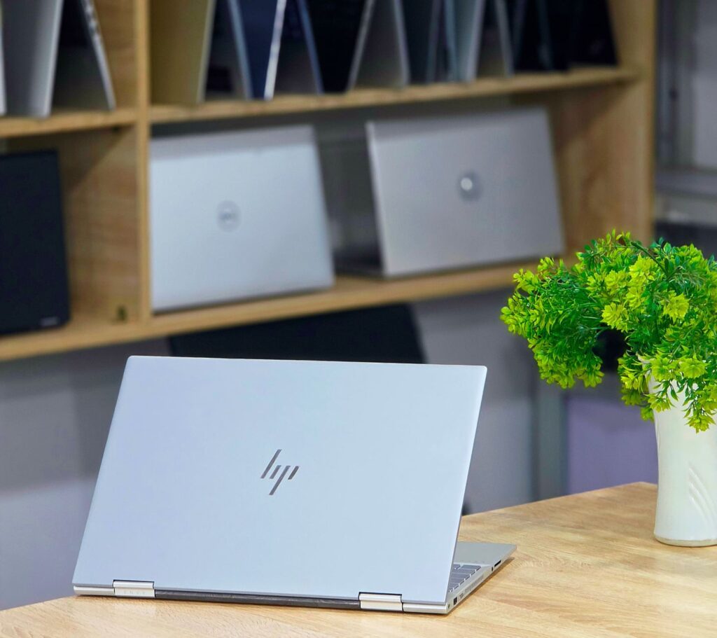 Open laptop on a wooden desk with a plant, conveying a modern and professional workspace.