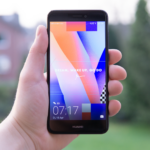 Hand holding a Huawei smartphone displaying a colorful screen outdoors in Germany.