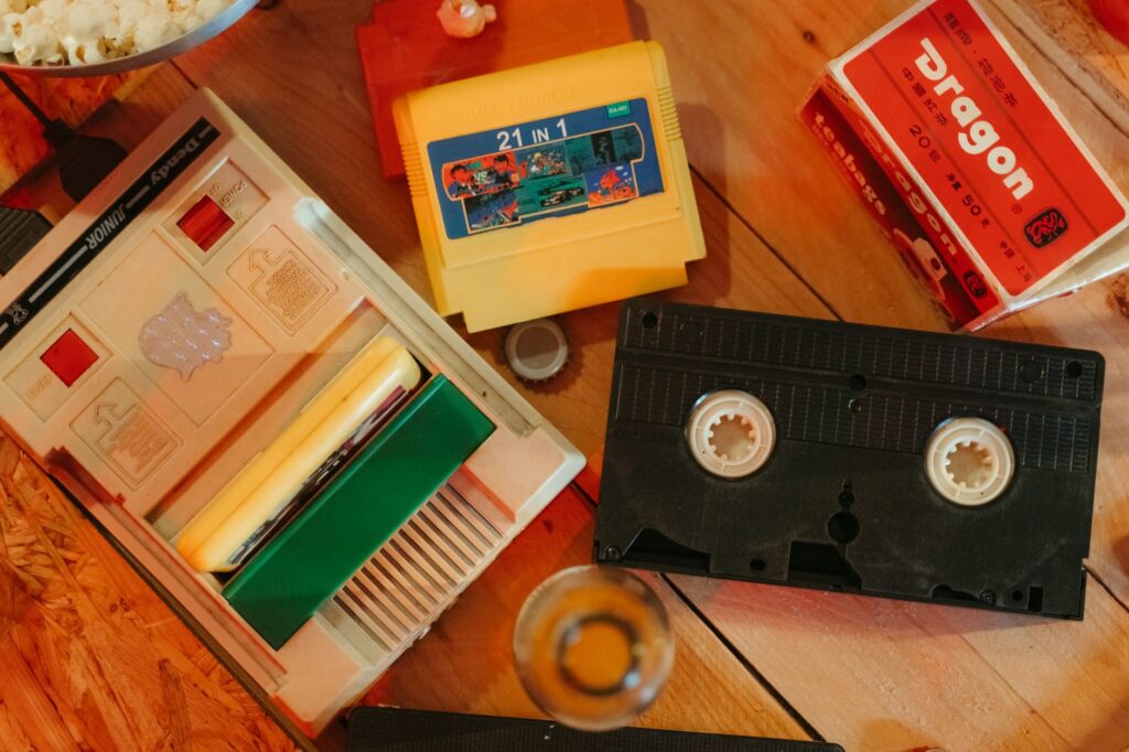 Vintage gaming console with cartridges and VHS tape on wooden surface, nostalgic theme.