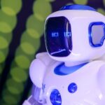Close-up of a modern humanoid robot with glowing blue features on a green abstract background.