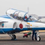 Training jet with Japanese insignia taxiing for preparation on airfield.