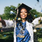 African American woman celebrating graduation with confetti outdoors, filled with happiness and success.