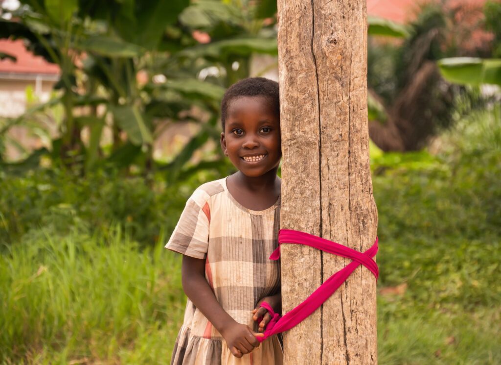 A happy African child smiles while standing outdoors, creating a joyful and vibrant scene.