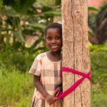 A happy African child smiles while standing outdoors, creating a joyful and vibrant scene.