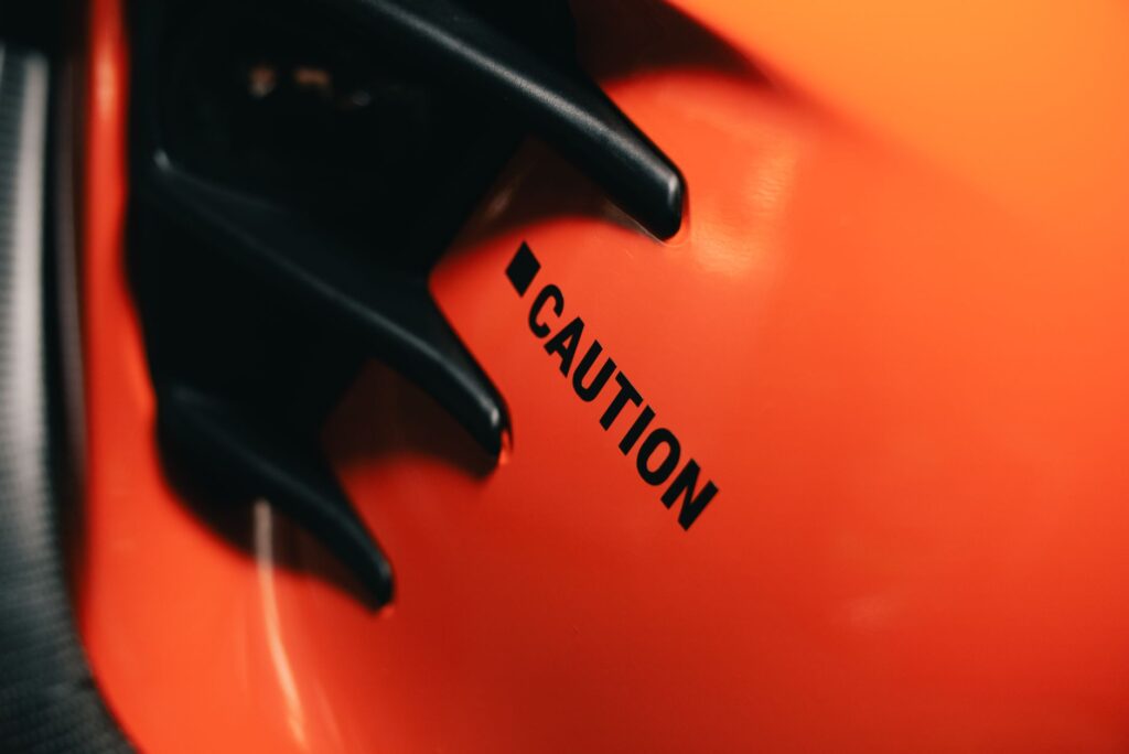 A close-up view of an orange surface with a caution sign. Represents safety and awareness.