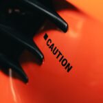 A close-up view of an orange surface with a caution sign. Represents safety and awareness.