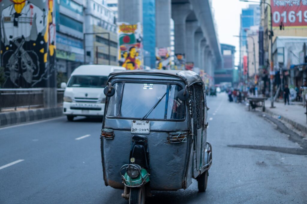 Colorful Dhaka street scene featuring a rickshaw, urban art, and modern infrastructure.