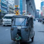 Colorful Dhaka street scene featuring a rickshaw, urban art, and modern infrastructure.