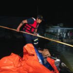 A rescue worker in Phú Yên, Vietnam, aids flood victims during nighttime operations.