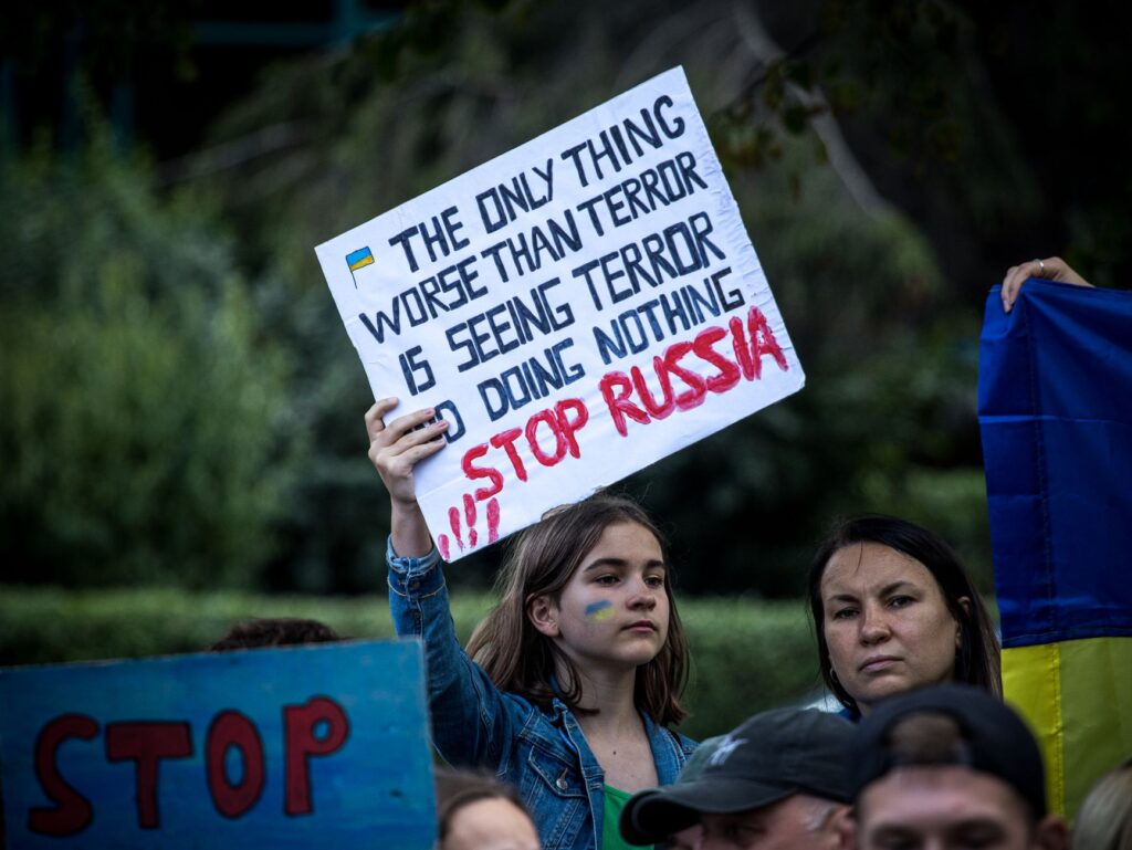 A demonstration featuring people holding banners supporting Ukraine and protesting against Russia.