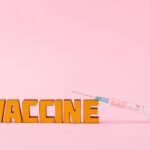 Close-up of a syringe and vaccine vial on a pink backdrop for health concepts.