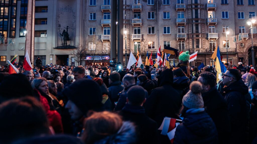 Crowd gathered peacefully in Vilnius with flags supporting Ukraine, urging for peace and unity.