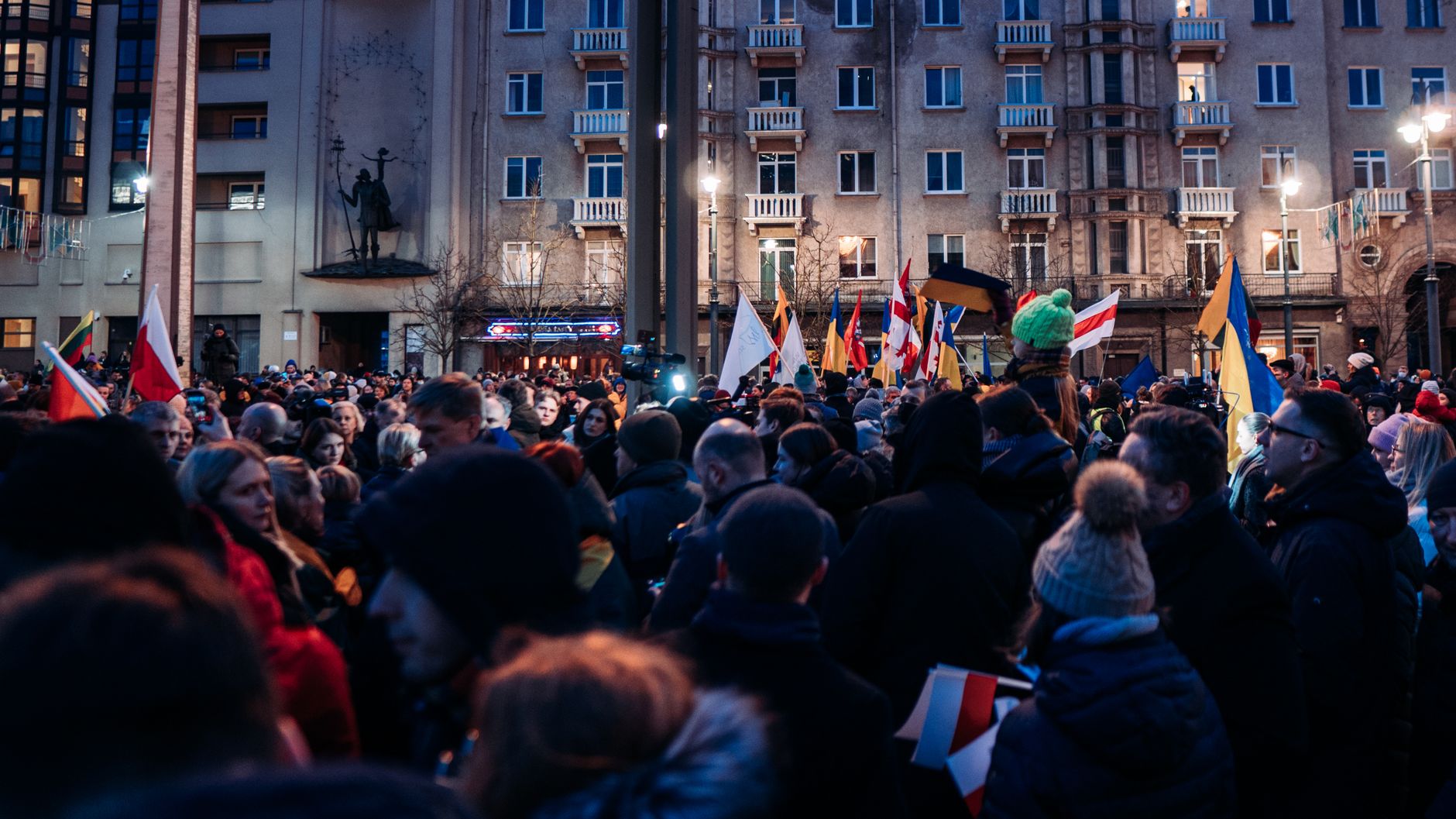 Crowd gathered peacefully in Vilnius with flags supporting Ukraine, urging for peace and unity.