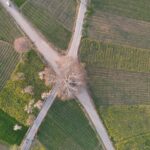 Detailed aerial shot of crossroads surrounded by lush green farmland.