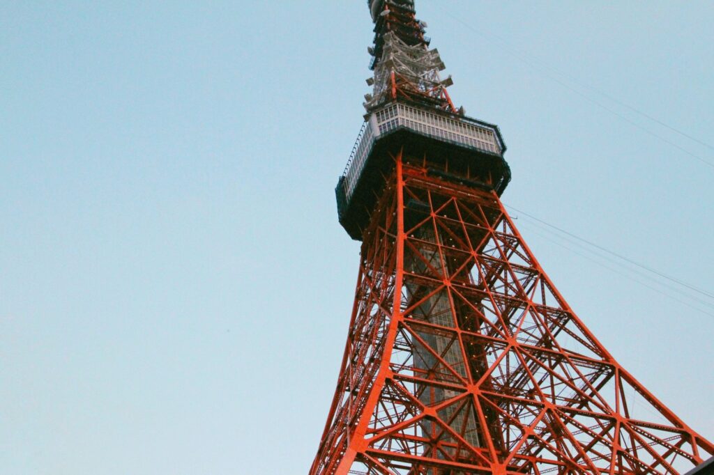 A low-angle view of Tokyo Tower with its iconic red structure set against a clear sky.