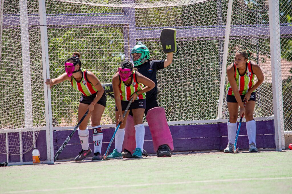 Female field hockey players in action defending the goal during a match.