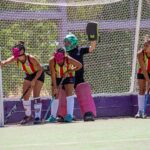 Female field hockey players in action defending the goal during a match.