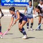 Female athletes engaged in a dynamic field hockey match, showcasing teamwork and competitive spirit.
