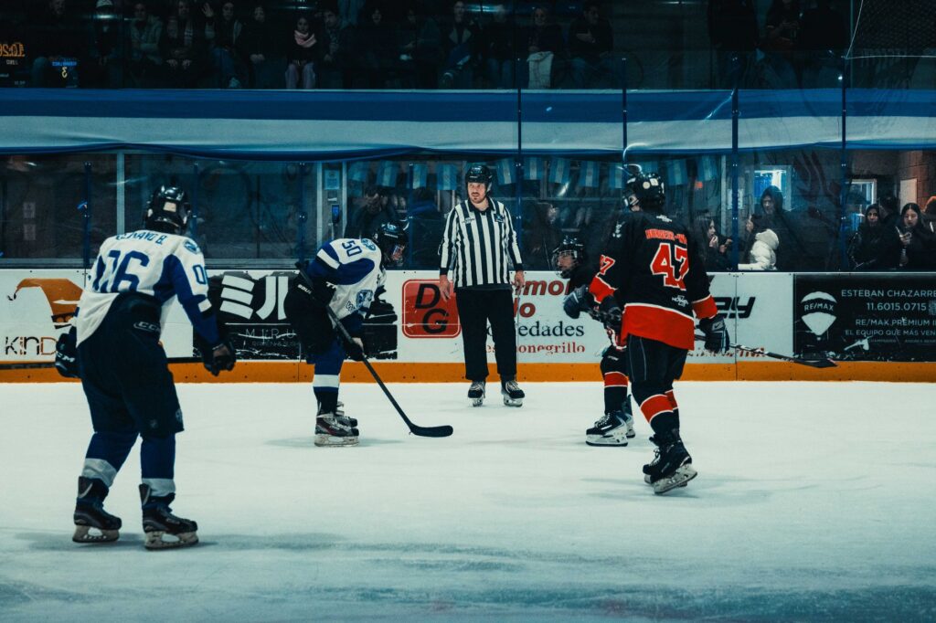 Dynamic ice hockey game captured during a faceoff in a Buenos Aires indoor arena.