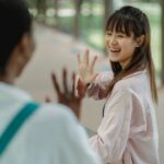 Young cheerful best multiethnic friends waving hands while saying hello to each other on pavement