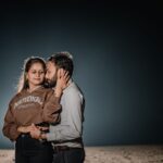 A couple shares a tender moment under a night sky, showcasing love and connection.