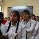 Group of Indian schoolgirls attentively listening in their classroom wearing uniforms.
