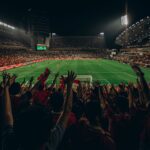 Lively football match with cheering fans in Abu Dhabi stadium at night.