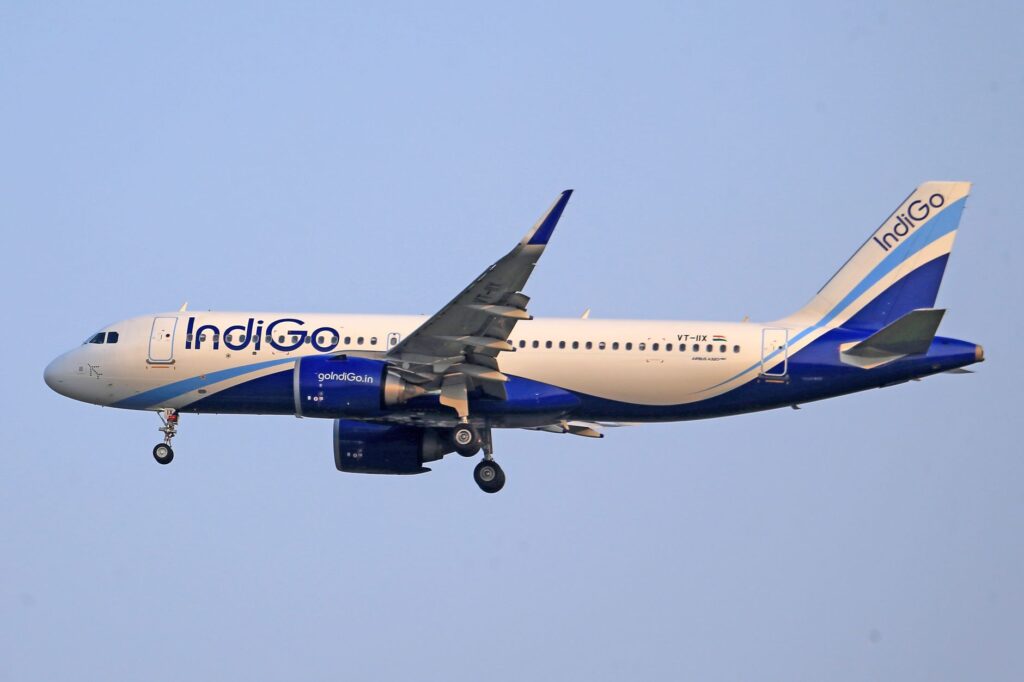 Indigo Airlines airplane flying through clear sky during daytime, showcasing aviation travel.