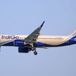 Indigo Airlines airplane flying through clear sky during daytime, showcasing aviation travel.