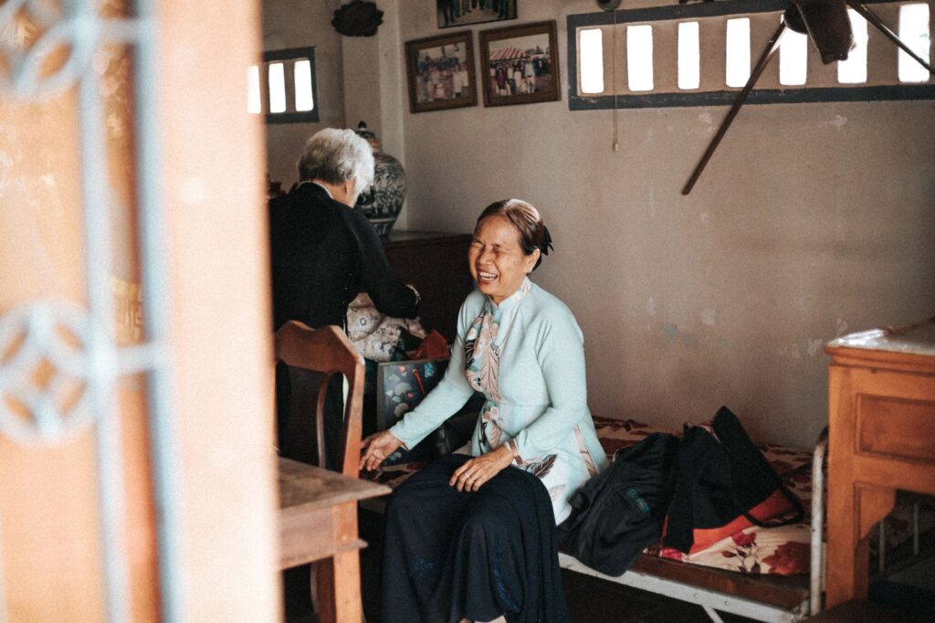 Two elderly women sharing a joyful moment in a cozy room setting, showcasing warmth and companionship.