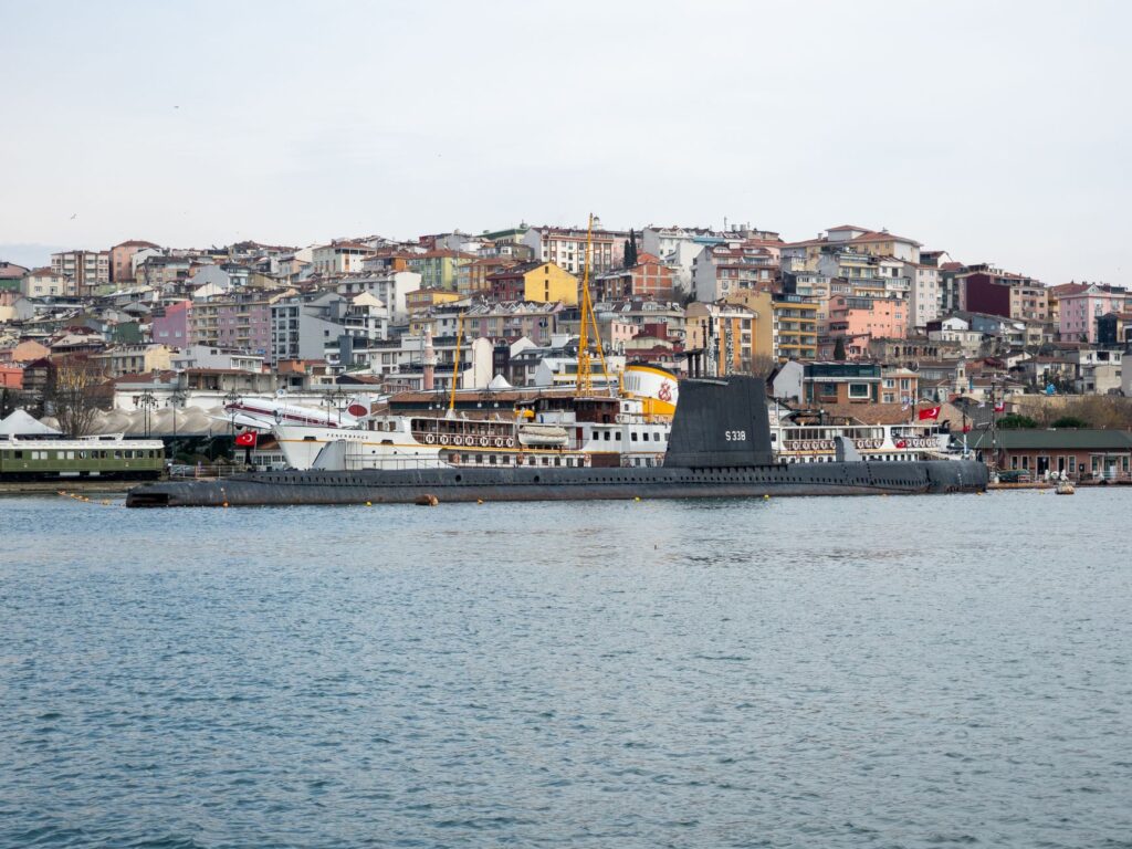 Panoramic view of Istanbul harbor showcasing a historical submarine against colorful cityscape.
