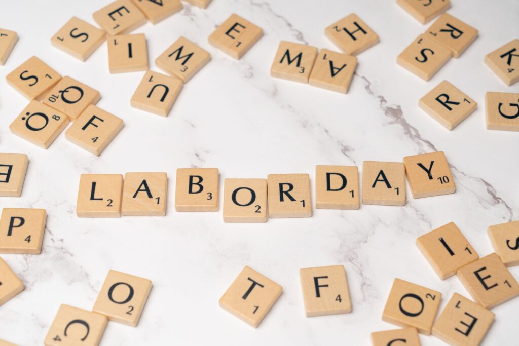 Labor Day spelled with Scrabble tiles on a marble surface, symbolizing celebration and creativity.