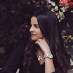 Stylish woman in Casablanca enjoying a moment outdoors surrounded by vibrant flowers.