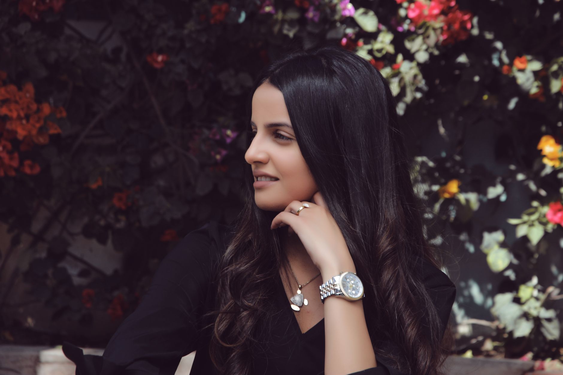 Stylish woman in Casablanca enjoying a moment outdoors surrounded by vibrant flowers.