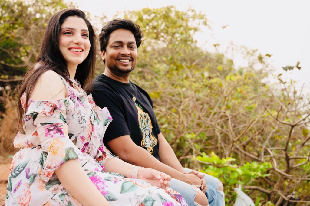 Happy couple sitting together outdoors, smiling amid greenery.