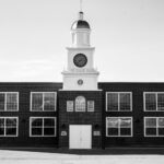 Monochrome image of a clock tower on a classic brick building with clear sky.
