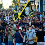 A vibrant demonstration with flags and photographers on a street in Gaza.