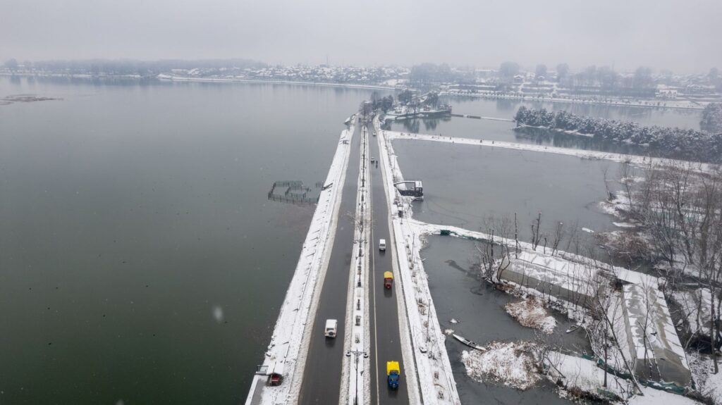 Aerial shot of a snow-covered bridge and road in Srinagar, Kashmir, during winter.