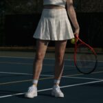 Woman holding a tennis racket and ball on an outdoor court, ready to play.