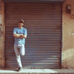 Man in blue shirt posing casually against a roller shutter in Sialkot, Pakistan.