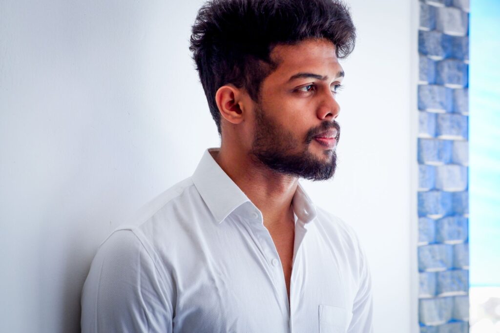 Close-up portrait of a thoughtful man looking away in a white shirt indoors.