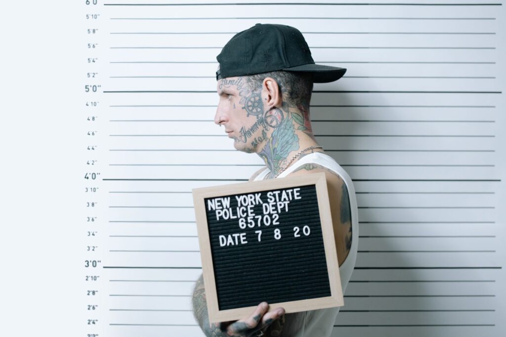 Side view of tattooed man holding mugshot board in police lineup.