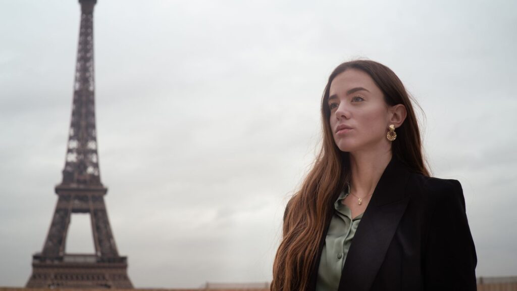 Young woman posing near the Eiffel Tower on a cloudy day in Paris.