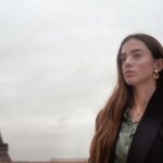 Young woman posing near the Eiffel Tower on a cloudy day in Paris.