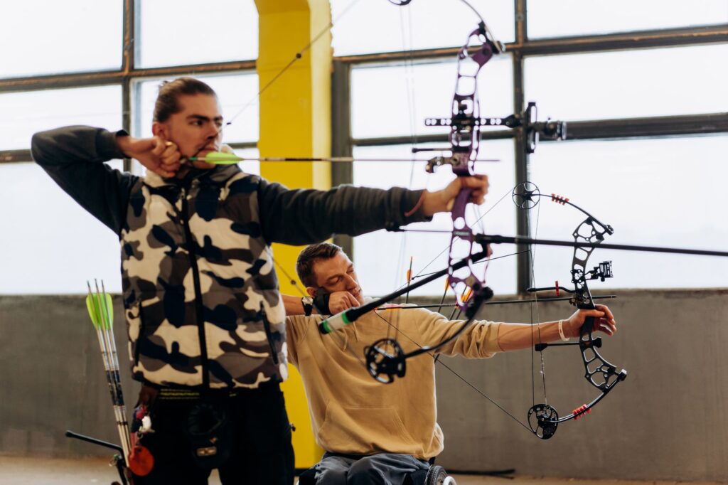 Two archers concentrate intensely during an indoor archery competition, showcasing skill and determination.