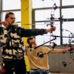 Two archers concentrate intensely during an indoor archery competition, showcasing skill and determination.